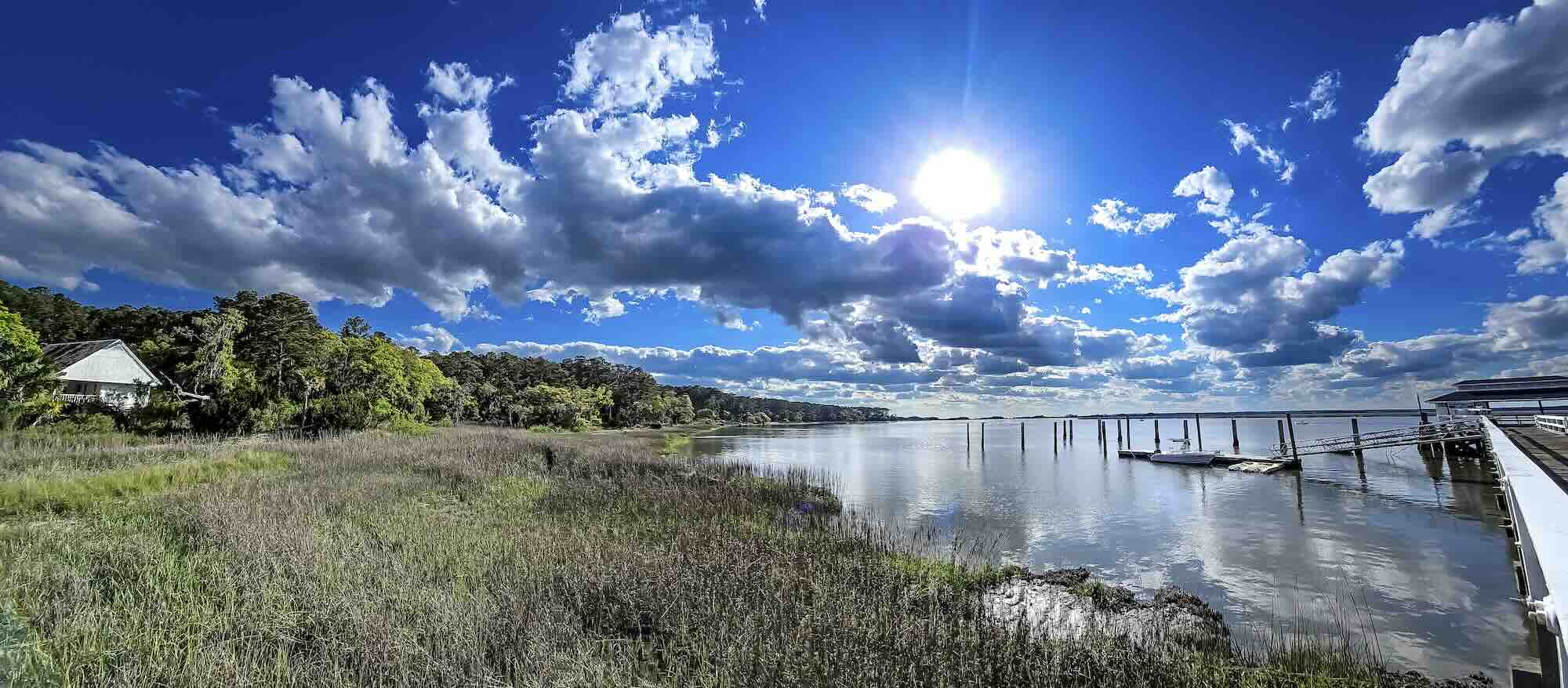 Scenic sunny lakeside view with clouds and dock.