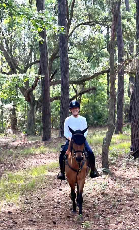 Person horseback riding in a forest trail