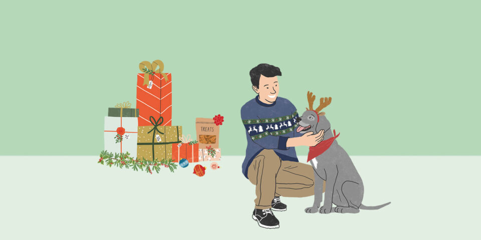 Man with dog in reindeer antlers and gifts.