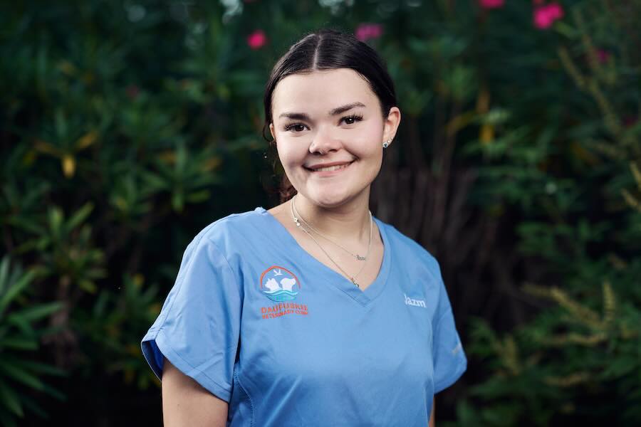 Smiling woman in blue scrubs with plants background.