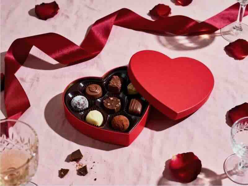 Heart-shaped box of assorted chocolates on table.